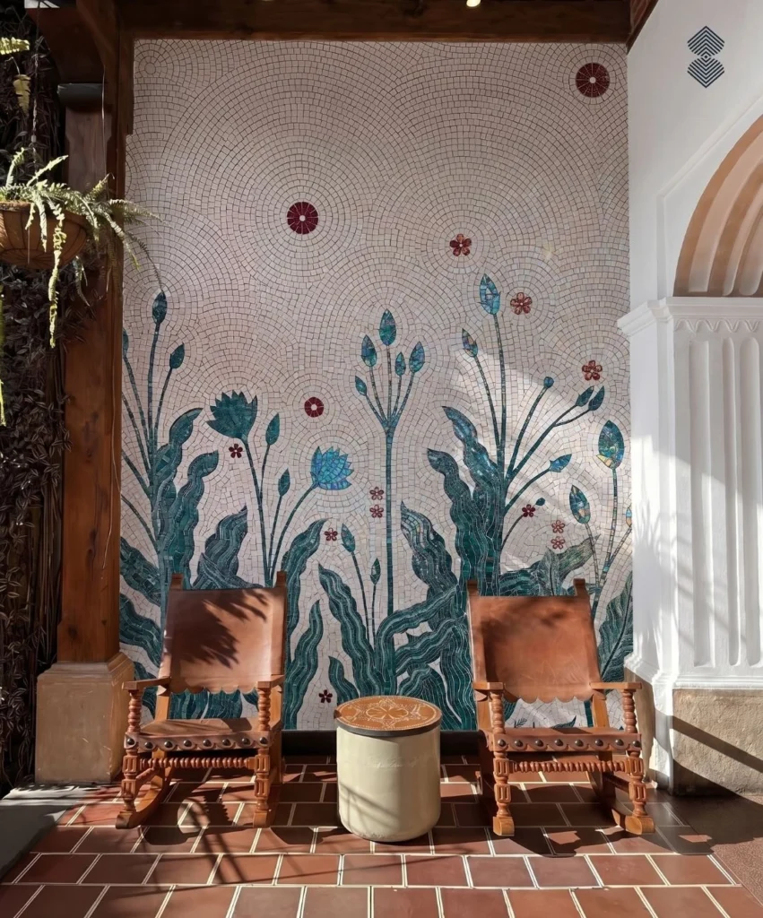 Handcrafted botanical mosaic mural with teal leaves, tall flowers, burgundy blossoms, and flowing ivory background tesserae.