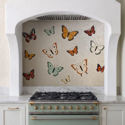 Saffron Wing glass and marble mosaic backsplash featuring colorful butterflies in orange, sage and cream against a soft ivory mosaic background.