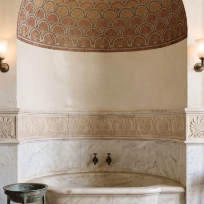Thermae Reserve classical marble mosaic featuring layered scallop and fan patterns in terracotta, beige, gold, brown, and muted blue-grey tones.