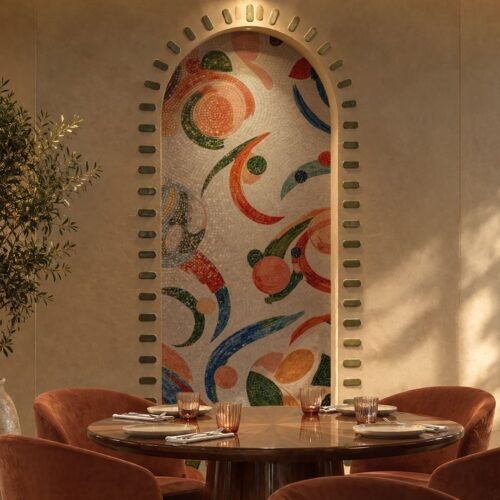 An abstract floral archway mosaic in terracotta, green and blue tones set into a curved wall niche above a restaurant table
