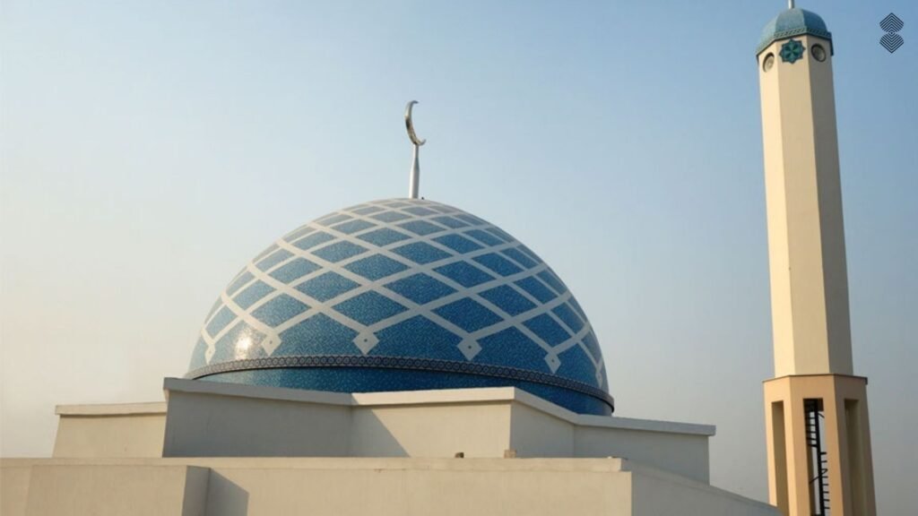 A light blue mosque dome featuring a white crisscross diamond pattern, located next to a minimalist beige minaret.