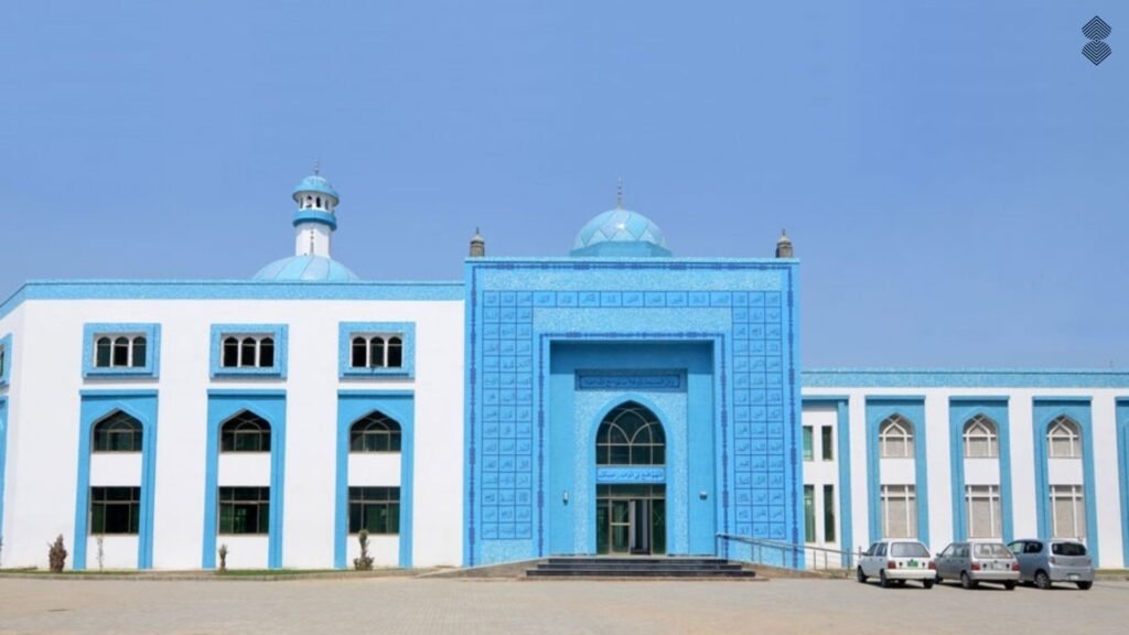 A large, flat-roofed white mosque accented with bright blue tiled entryways, window frames, and domes.
