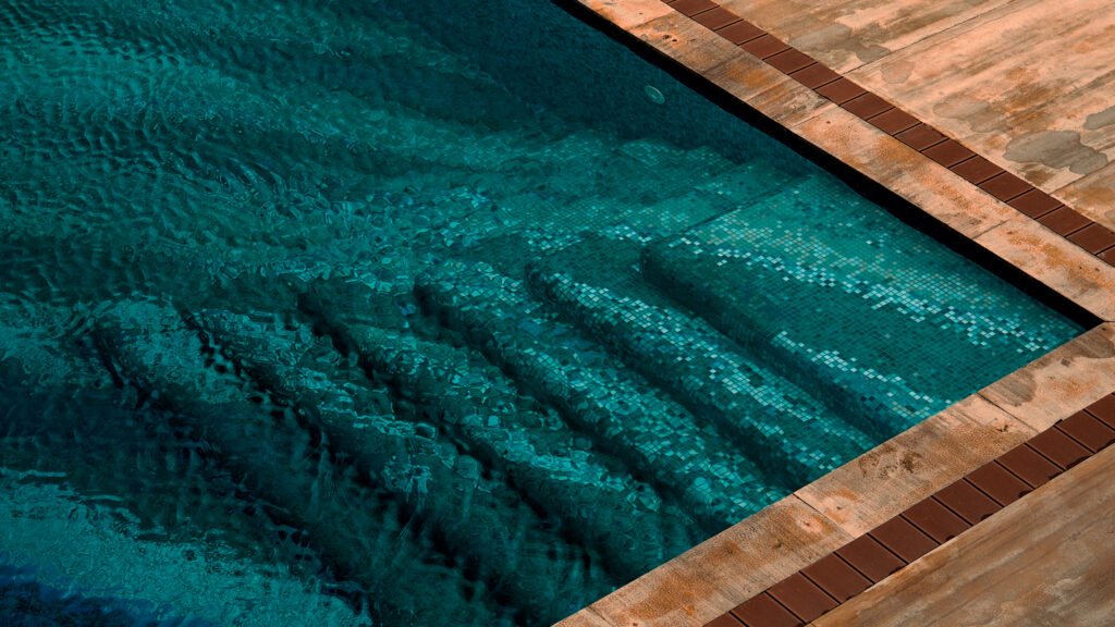 Close-up of a pixel mosaic pool design with deep teal pool steps lined with micro mosaic glass tiles under rippling water.