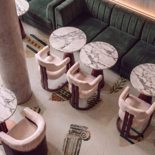 Classical column floor mosaic depicting an Ionic capital fragment set within a stone-paved cafe floor