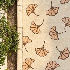 Ginkgo leaf walkway mosaic with scattered tan and terracotta leaf tesserae on a crackled ivory stone path