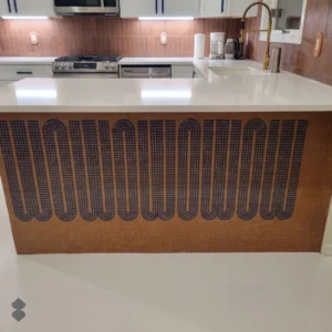 Handcrafted geometric mosaic kitchen island with dark looping arches set against a warm terracotta tesserae background.