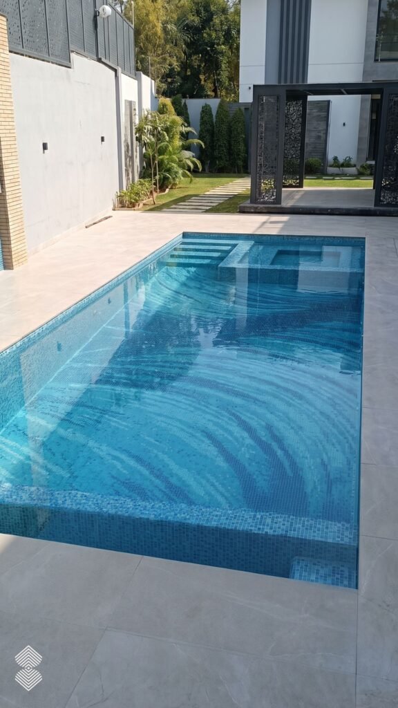 Rectangular outdoor pool lined with light blue glass tiles featuring a wave mosaic design on the floor.