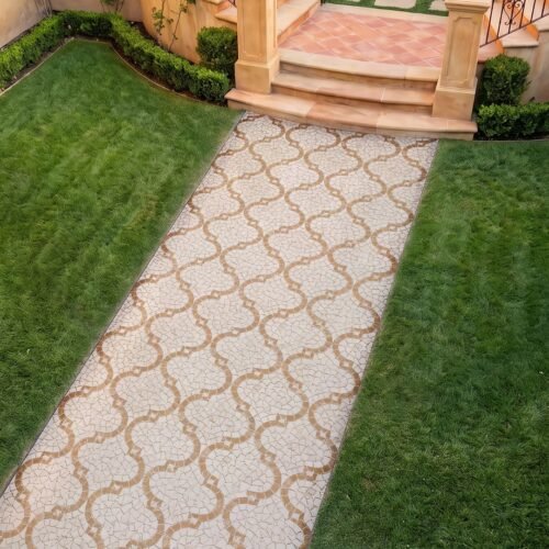 A quatrefoil walkway mosaic in cream and tan stone tesserae laid as a garden path runner