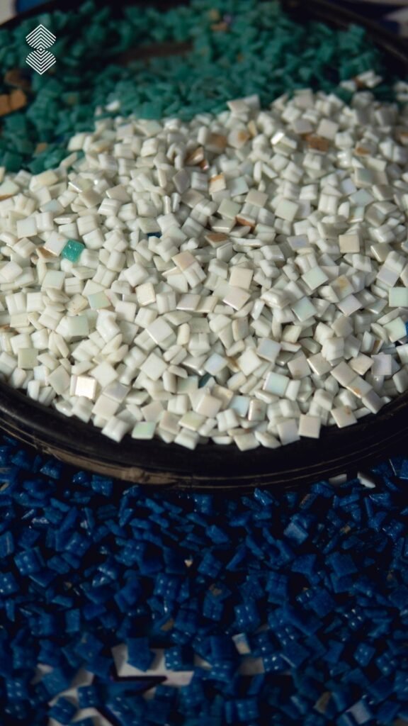 A close-up of hundreds of tiny, square mosaic tiles in white, teal, and deep blue, sorted into distinct piles.