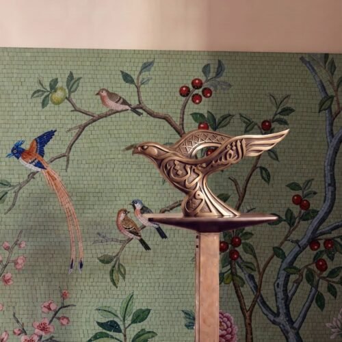 A chinoiserie bird mosaic mural on a sage green wall shows songbirds perched among berry branches and blossoms.