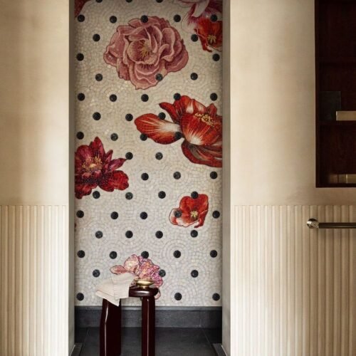 A floral polka dot mosaic panel with pink and red roses set against a black dot pattern, installed in a recessed wall niche.