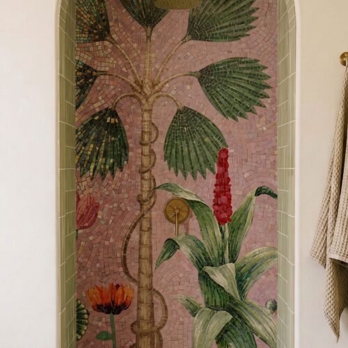 A palm tree mosaic mural with fan leaves and tropical flowers set against a pink background in an arched niche.