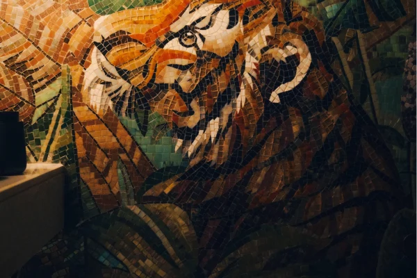 Majestic Tiger mosaic mural with jungle leaves in warm orange and green tones installed on a bathroom wall.